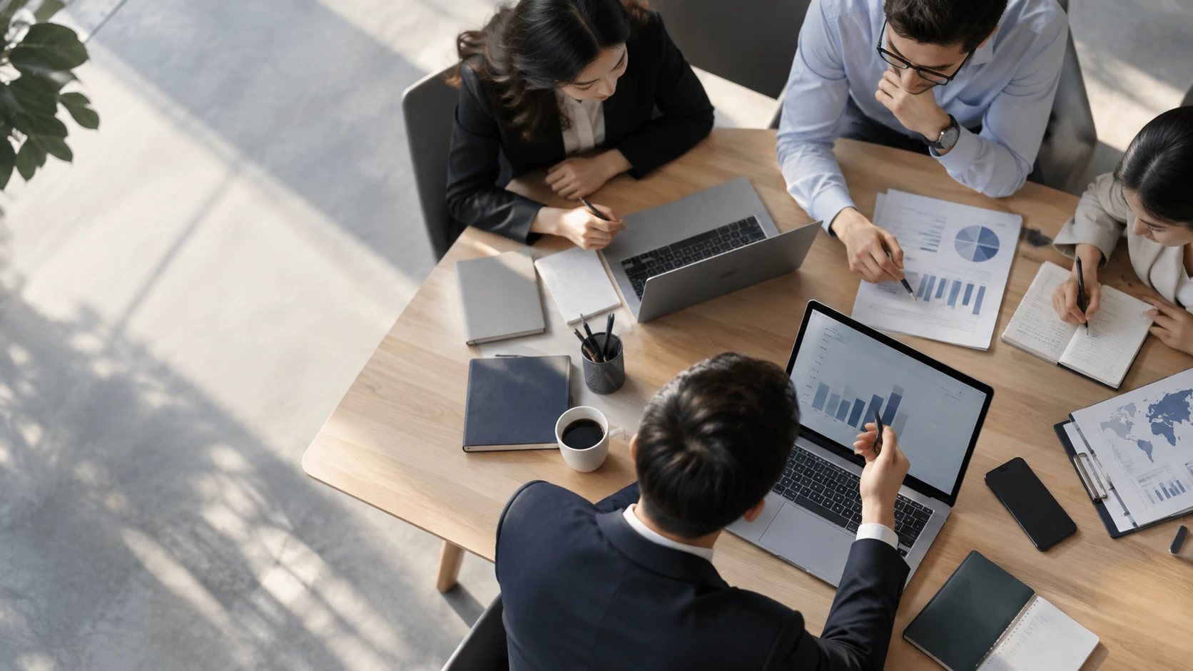 A team collaborating on cross-border business around a laptop and financial charts