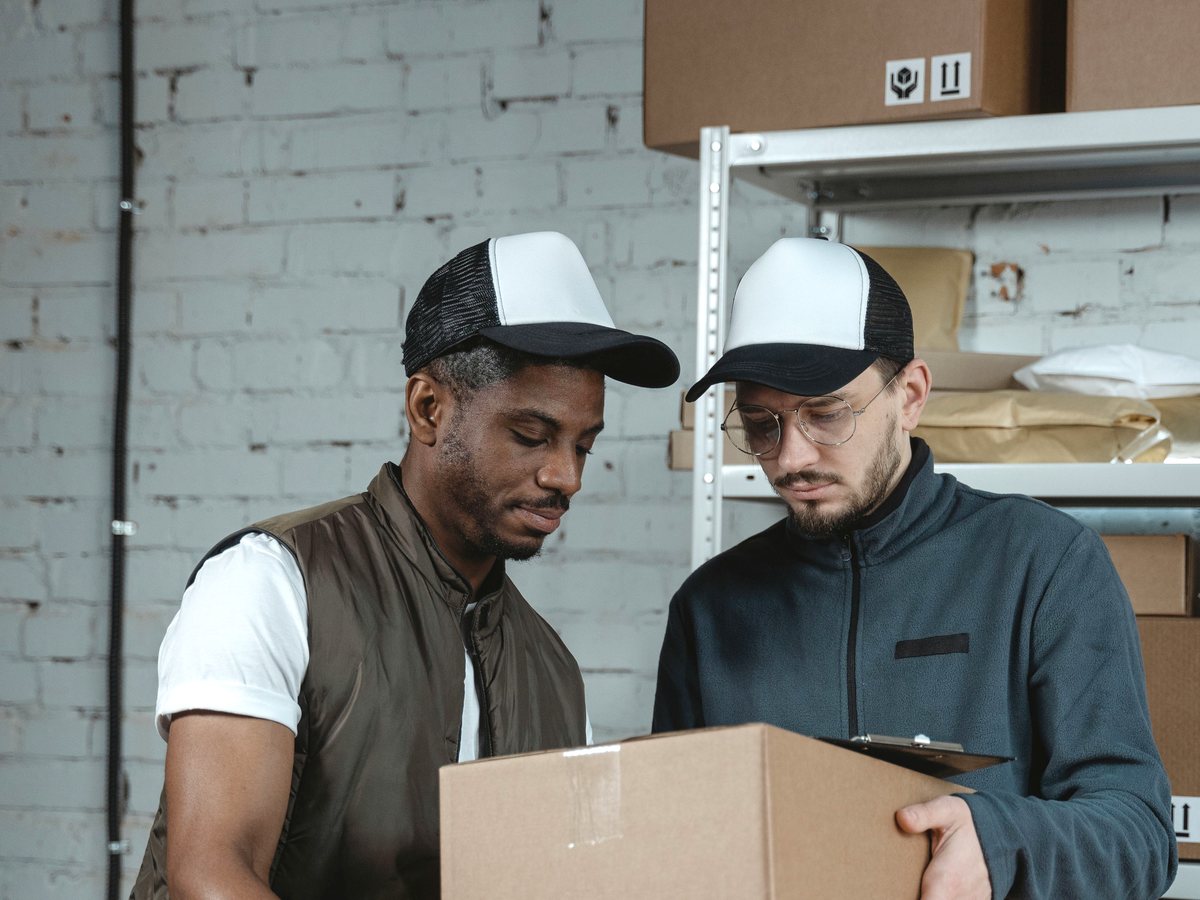 Warehouse colleagues checking sourcing documents beside goods